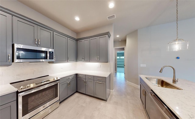 kitchen featuring sink, backsplash, appliances with stainless steel finishes, and gray cabinets