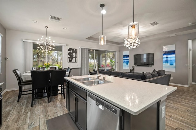 kitchen featuring stainless steel dishwasher, pendant lighting, a center island with sink, and a chandelier