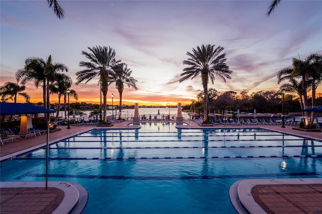 pool at dusk featuring a patio area and a water view