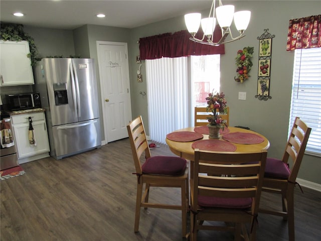 dining space with dark wood-type flooring, a healthy amount of sunlight, and a chandelier