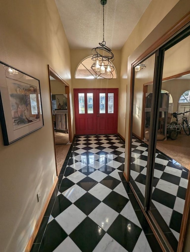 carpeted entrance foyer with a healthy amount of sunlight, a notable chandelier, and a textured ceiling