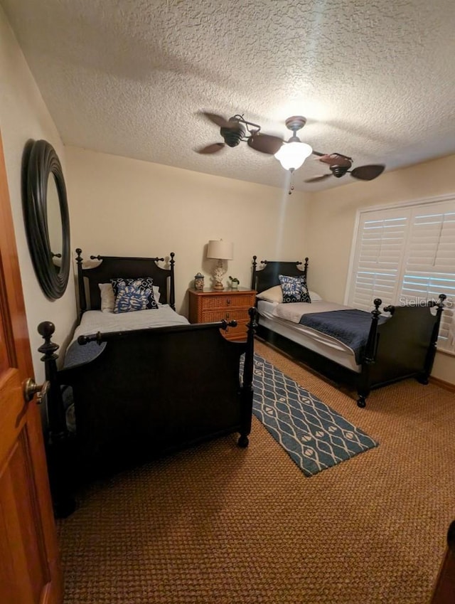 bedroom featuring a textured ceiling, ceiling fan, and dark colored carpet