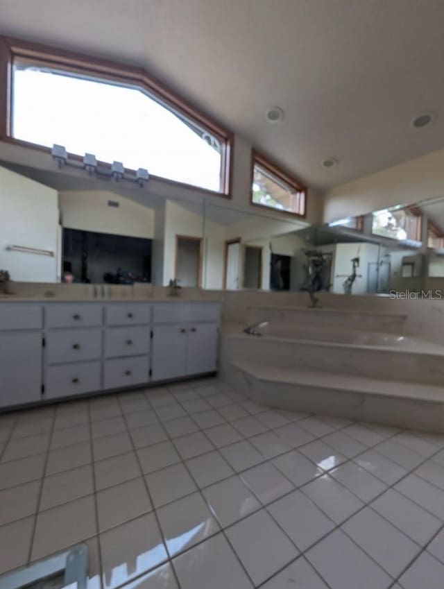 bathroom featuring oversized vanity, tile floors, vaulted ceiling, and a bath to relax in