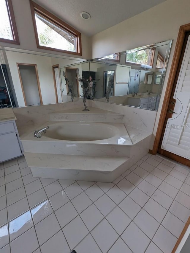 bathroom featuring a bath to relax in, vaulted ceiling, large vanity, and tile flooring