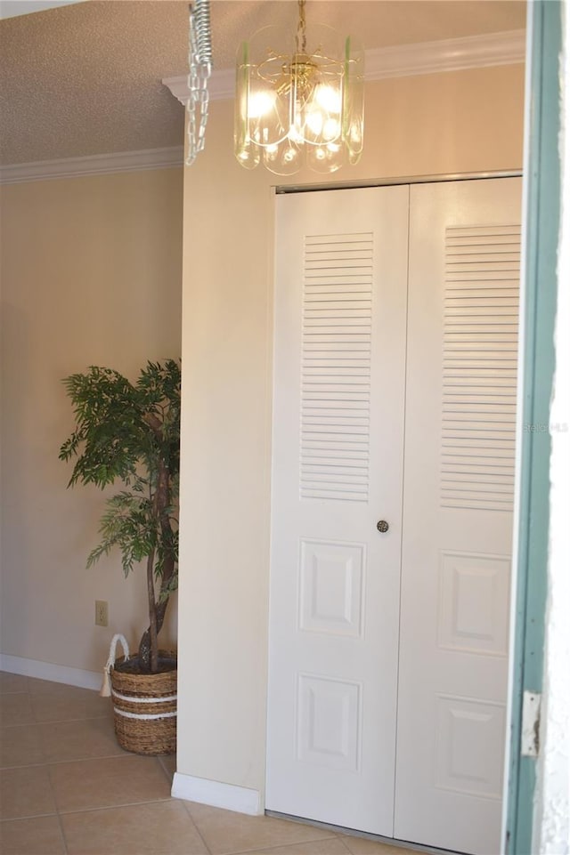 tiled entryway featuring ornamental molding, a textured ceiling, and an inviting chandelier