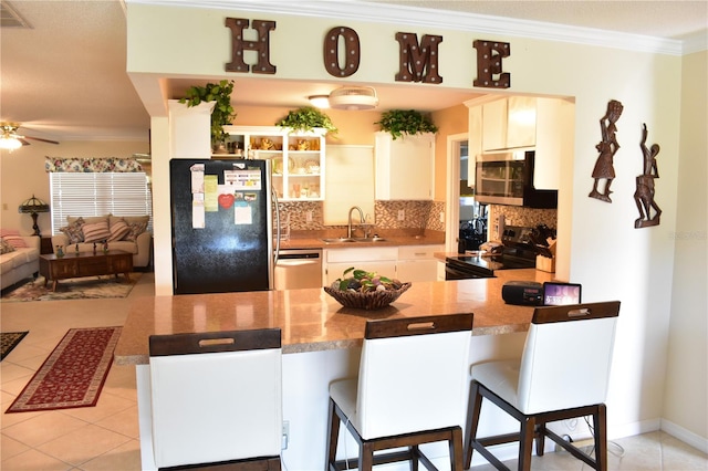 kitchen featuring a kitchen breakfast bar, ceiling fan, kitchen peninsula, black appliances, and backsplash