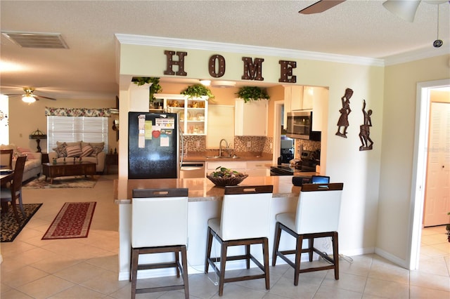 kitchen with electric stove, black refrigerator, a kitchen bar, and ceiling fan