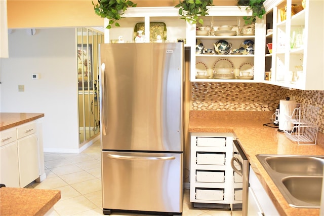 kitchen with light tile floors, white cabinetry, backsplash, and stainless steel fridge