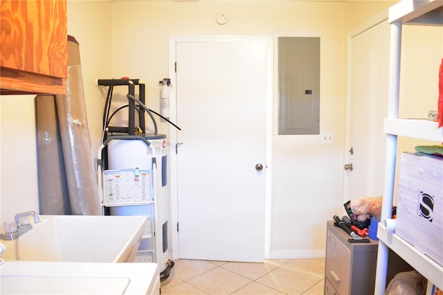 laundry area with electric water heater, sink, and light tile floors