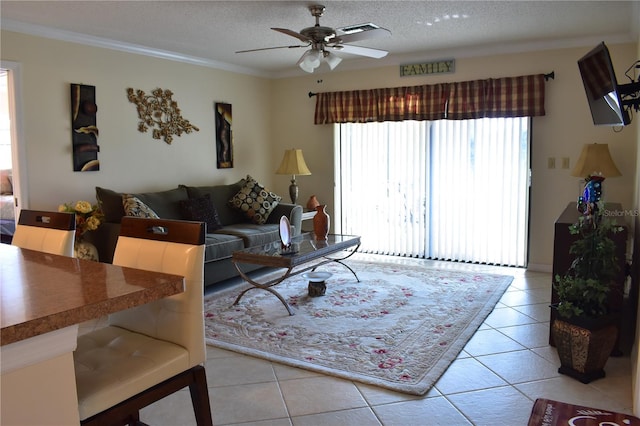 living room with a textured ceiling, crown molding, ceiling fan, and light tile flooring