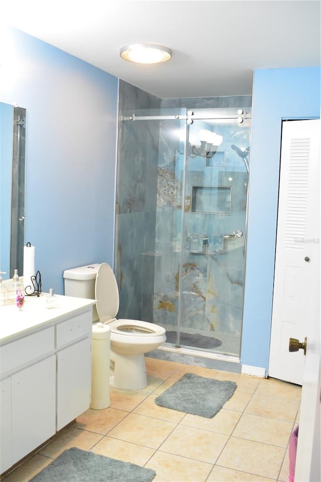 bathroom with toilet, tile floors, a shower with shower door, and vanity