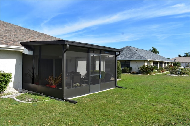 rear view of house featuring a yard and a sunroom