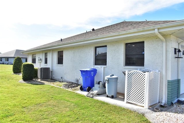 back of property with a yard and central AC