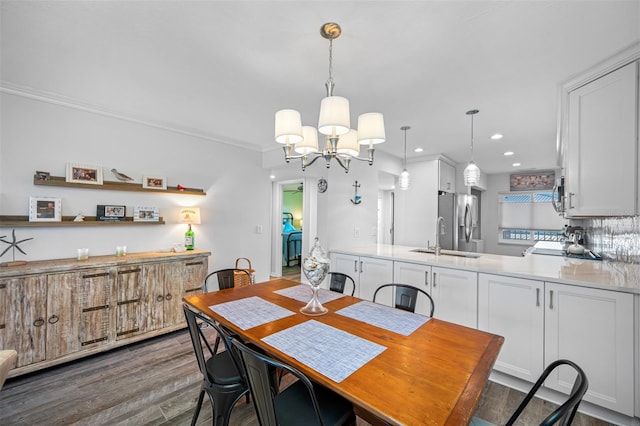 dining room with crown molding, dark wood-type flooring, a notable chandelier, and sink