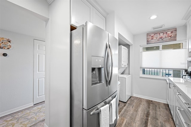 kitchen with white cabinets, dark hardwood / wood-style floors, stainless steel fridge with ice dispenser, and stacked washer and clothes dryer