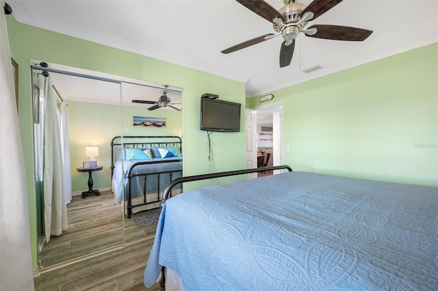 bedroom featuring a closet, ceiling fan, ornamental molding, and dark wood-type flooring