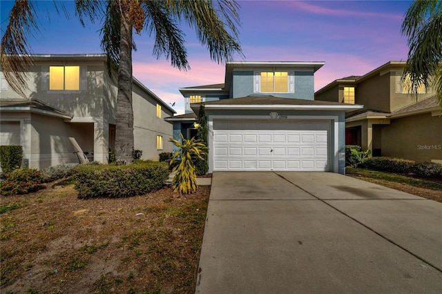 traditional-style house with an attached garage, driveway, and stucco siding