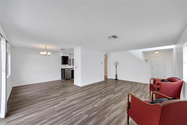 living room with hardwood / wood-style flooring, an inviting chandelier, and a textured ceiling