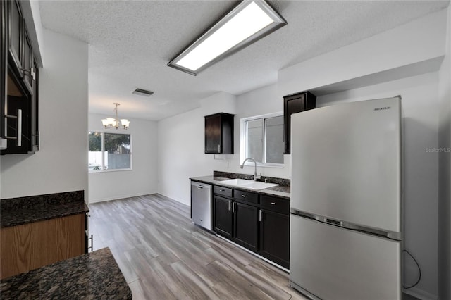 kitchen with light hardwood / wood-style flooring, stainless steel dishwasher, sink, a notable chandelier, and white fridge