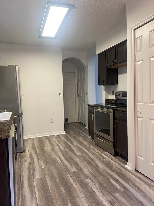 kitchen featuring stainless steel appliances, light hardwood / wood-style floors, and dark brown cabinetry