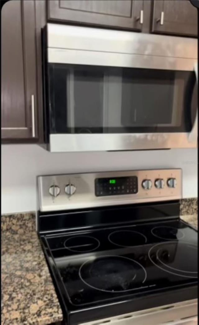 room details featuring dark stone countertops, stove, and dark brown cabinets