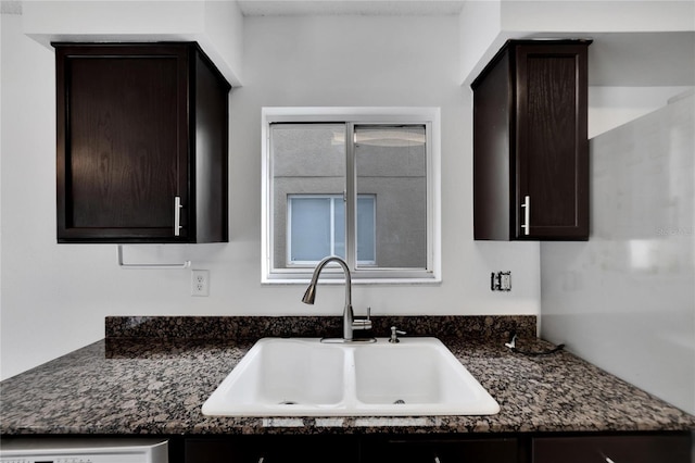 kitchen with sink, dark stone countertops, and dark brown cabinetry