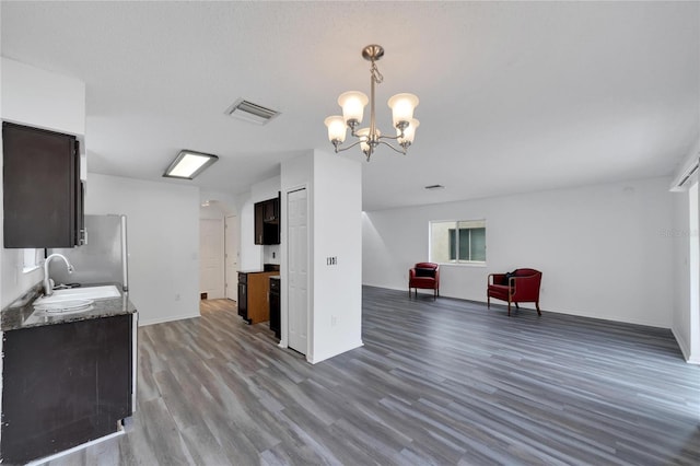 kitchen featuring a chandelier, hardwood / wood-style flooring, decorative light fixtures, sink, and stainless steel fridge