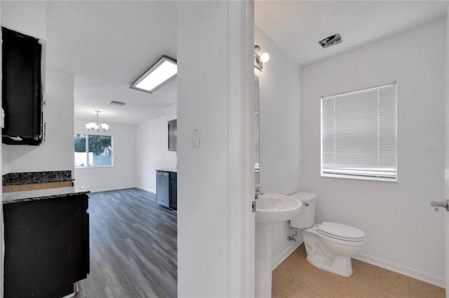 bathroom featuring a notable chandelier, toilet, and tile patterned floors