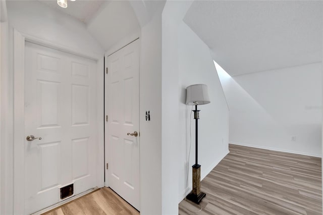 interior space with light hardwood / wood-style floors and vaulted ceiling