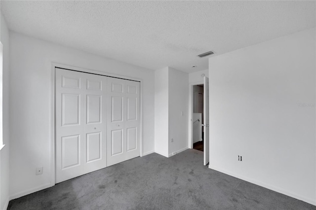 unfurnished bedroom featuring a textured ceiling, a closet, and dark colored carpet