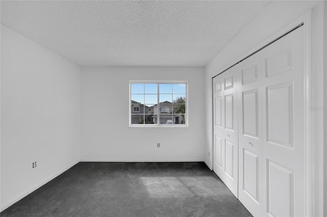 unfurnished bedroom with a textured ceiling, a closet, and dark carpet