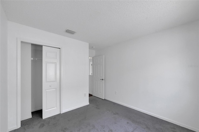 unfurnished bedroom with a closet, a textured ceiling, and dark colored carpet