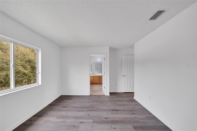 spare room featuring hardwood / wood-style flooring and a textured ceiling