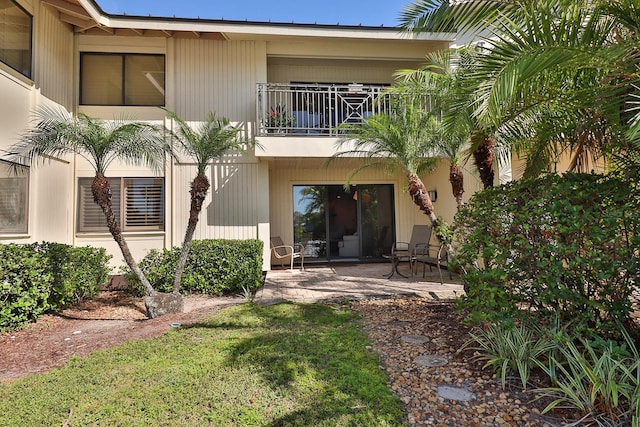 back of property with a patio, a balcony, and a lawn