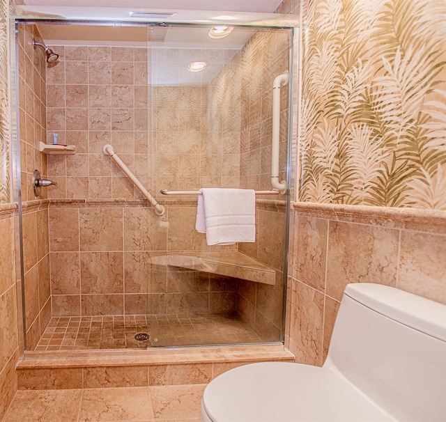 bathroom with walk in shower, toilet, and tile walls