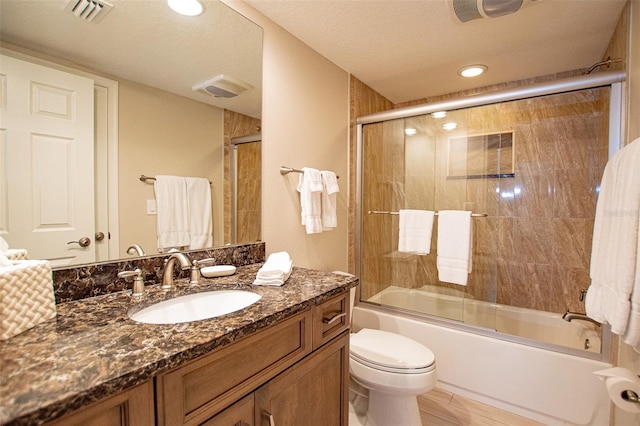 full bathroom featuring tile flooring, a textured ceiling, oversized vanity, combined bath / shower with glass door, and toilet