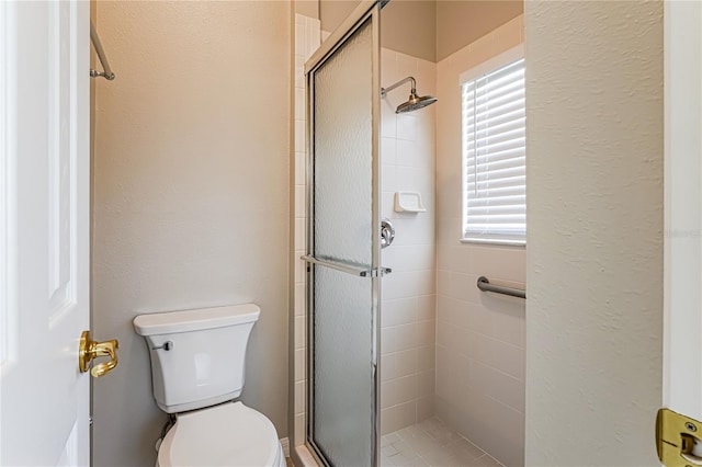 bathroom featuring toilet and a shower with door