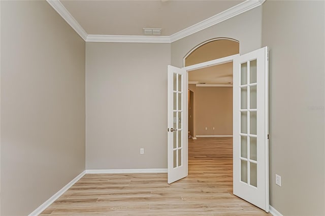 empty room featuring french doors, ornamental molding, and light hardwood / wood-style flooring