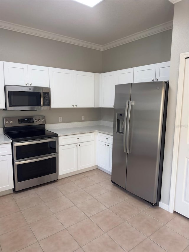 kitchen featuring white cabinets, appliances with stainless steel finishes, light tile patterned floors, and crown molding