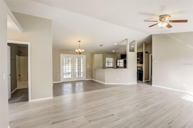 unfurnished living room with french doors, light tile flooring, ceiling fan with notable chandelier, and vaulted ceiling