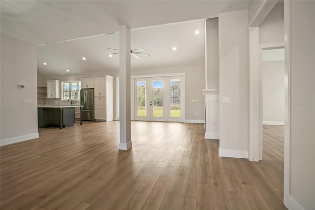 unfurnished living room featuring french doors, sink, ceiling fan, and hardwood / wood-style flooring