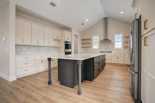 kitchen featuring wall chimney exhaust hood, light hardwood / wood-style floors, a kitchen island, and white cabinetry