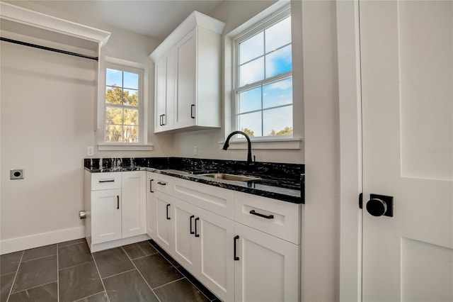 kitchen featuring dark stone counters, dark tile floors, white cabinets, and sink