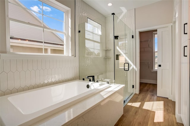 bathroom featuring shower with separate bathtub, a healthy amount of sunlight, and hardwood / wood-style flooring