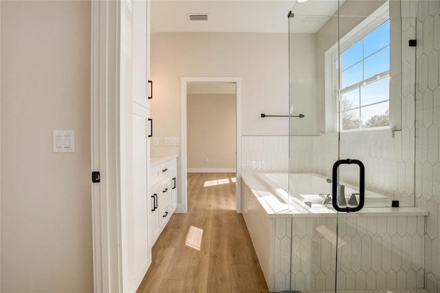 bathroom featuring wood-type flooring, separate shower and tub, and vanity