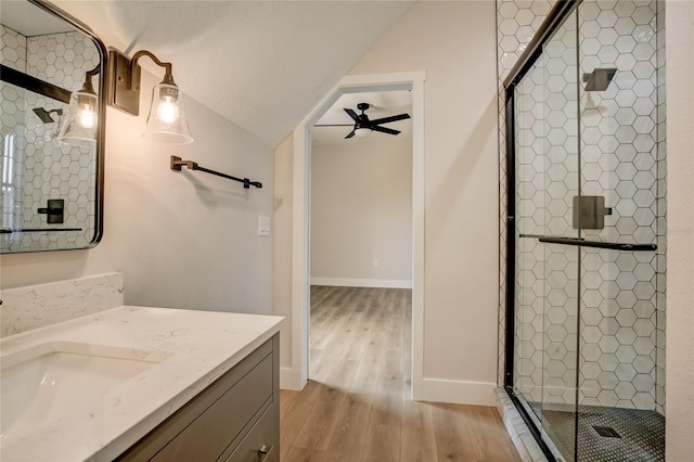 bathroom with an enclosed shower, hardwood / wood-style floors, ceiling fan, vaulted ceiling, and large vanity