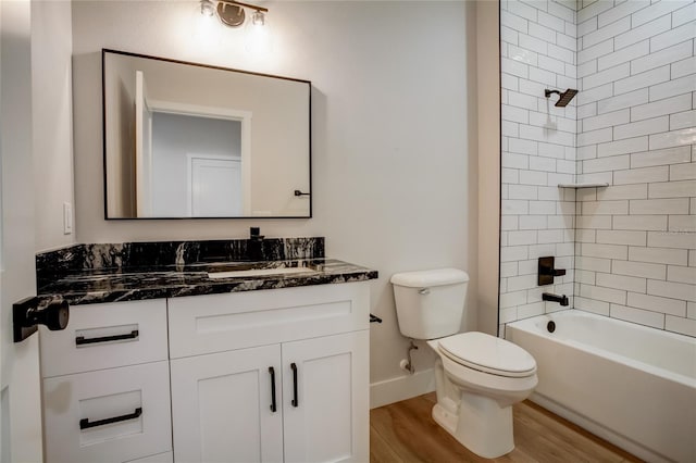 full bathroom with tiled shower / bath, toilet, hardwood / wood-style floors, and vanity