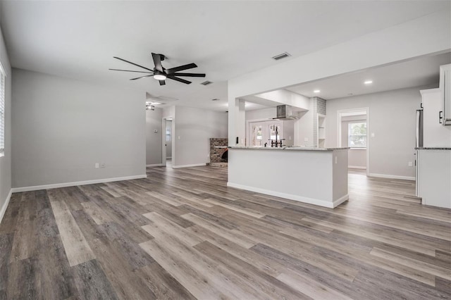 kitchen featuring light stone countertops, white cabinetry, ceiling fan, and hardwood / wood-style flooring