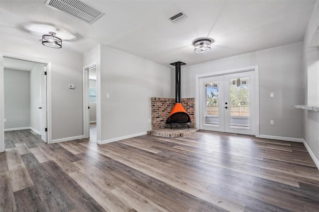 unfurnished living room with dark wood-type flooring, a wood stove, and french doors