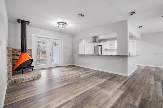 entrance foyer with french doors, light hardwood / wood-style floors, and a wood stove